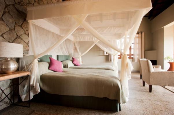 Bedroom with four-poster bed and mosquito net at Kitela Lodge, Karatu