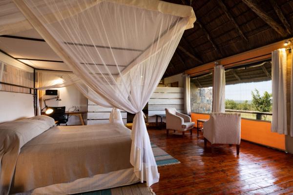 Bedroom with four-poster bed and bush views at Mara Mara Tented Lodge