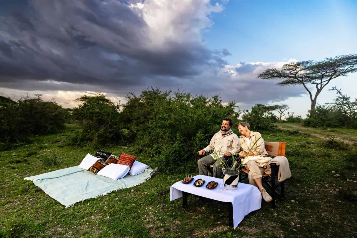 Couple enjoying a sundowner on the Ndutu plains with Nyumbu Luxury Camp