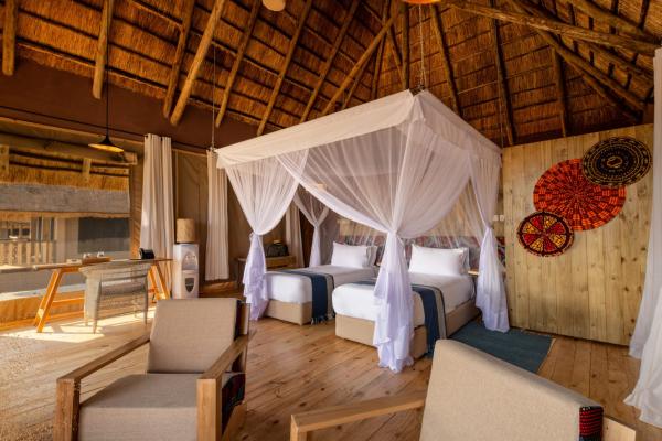 Tent interior with canopy bed and seating area at Lake Burunge Baobab South Lodge