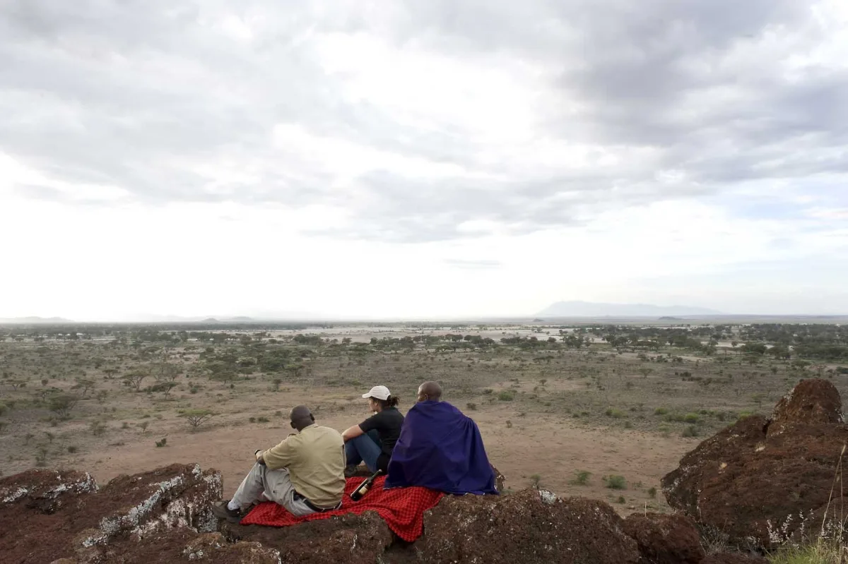 Guests with a Maasai guide on a hilltop in Enduimet