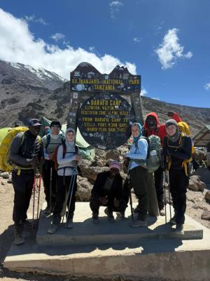 Ascensión al Kilimanjaro – Climbers celebrating at the Uhuru Peak summit sign, 5,895 m