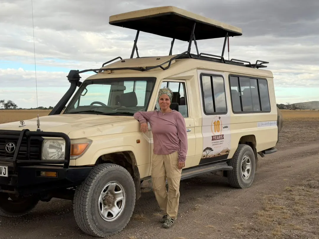 Visa & Entry Requirements – A guest standing beside an Exceptional Safaries Land Cruiser on safari