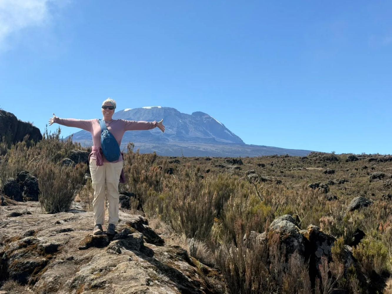 Mit dem Mountainbike am Kilimandscharo – A hiker on the Shira Plateau with Kilimanjaro’s Kibo summit behind