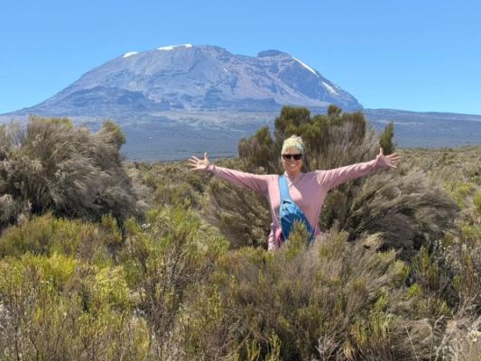 Mit dem Mountainbike am Kilimandscharo – A hiker celebrating in front of Kilimanjaro on the Shira Plateau