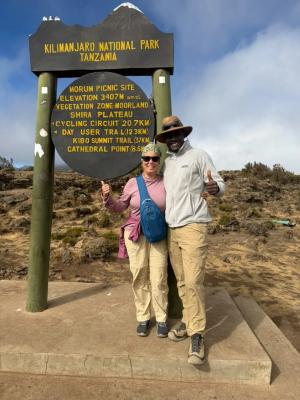 Mit dem Mountainbike am Kilimandscharo – Guest and guide at a Kilimanjaro National Park sign on the day hike