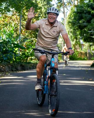 A rider cycling a garden lane through banana palms and forest near Lake Duluti