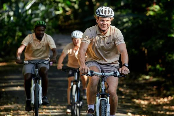 A group of riders cycling together along a leafy lane near Lake Duluti