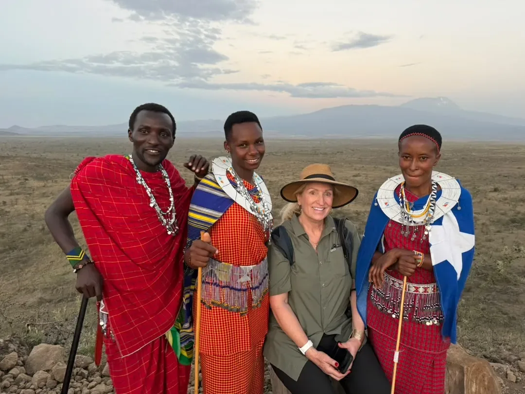 Osiligilai – A guest with Maasai hosts in beaded dress at sunset, the mountain behind