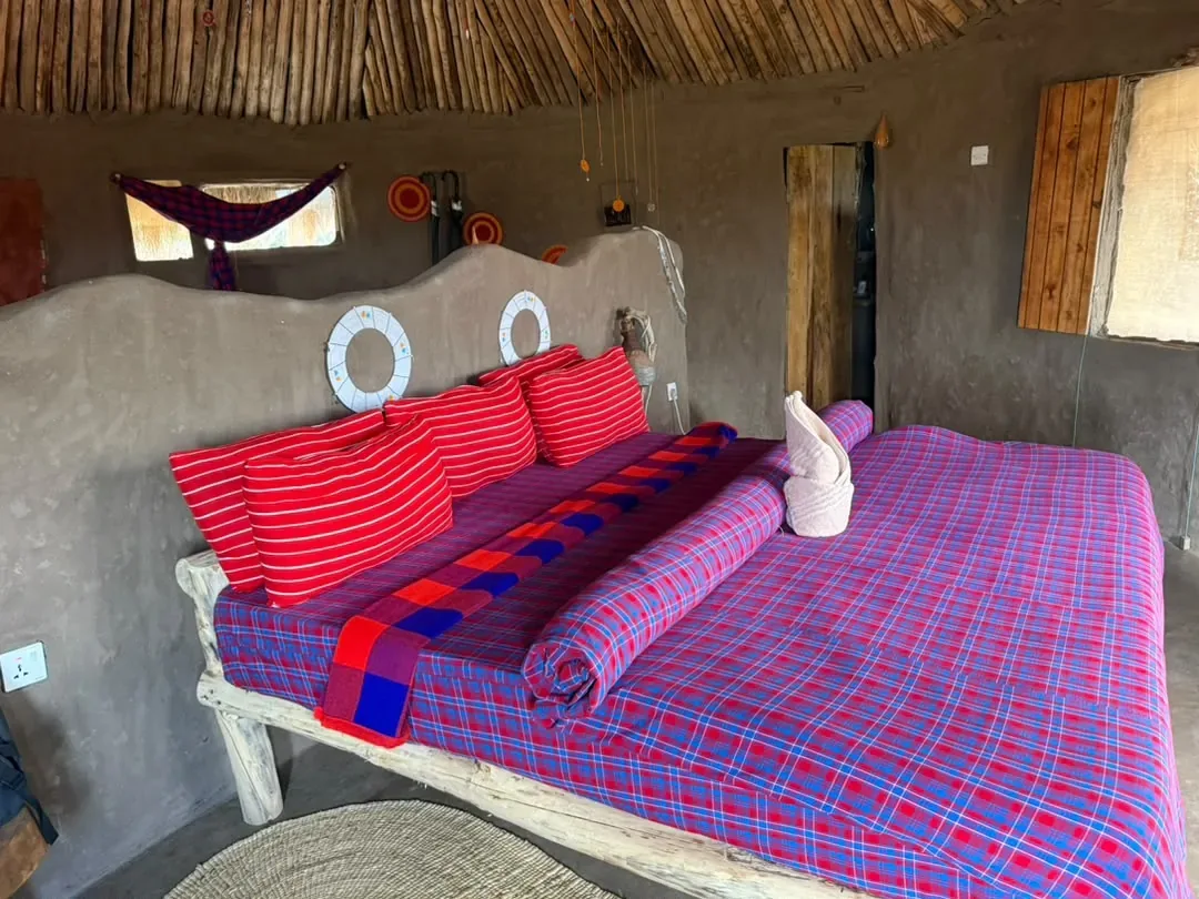 A cottage bedroom at Osiligilai dressed in red and purple Maasai shuka cloth