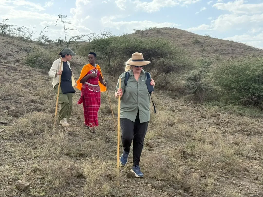 Osiligilai – Guests walking up a hillside with a Maasai woman guide