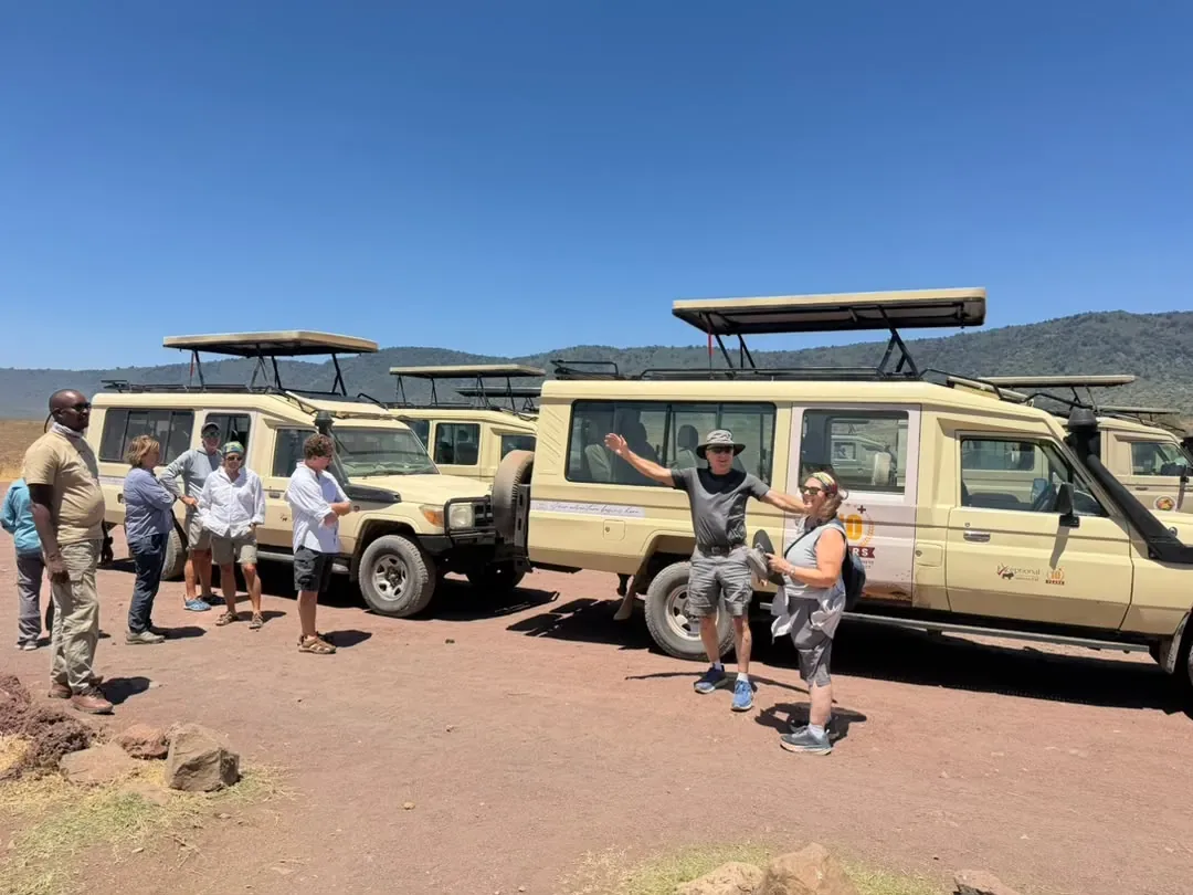 Ngorongoro-Krater – Guests stretching their legs beside the Land Cruisers on the crater rim road