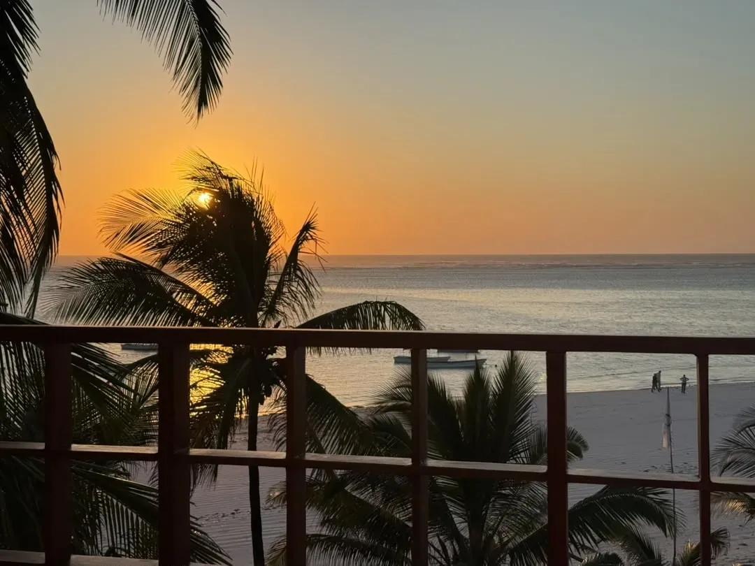 Sansibar – The sun setting over the beach from a palm-framed balcony