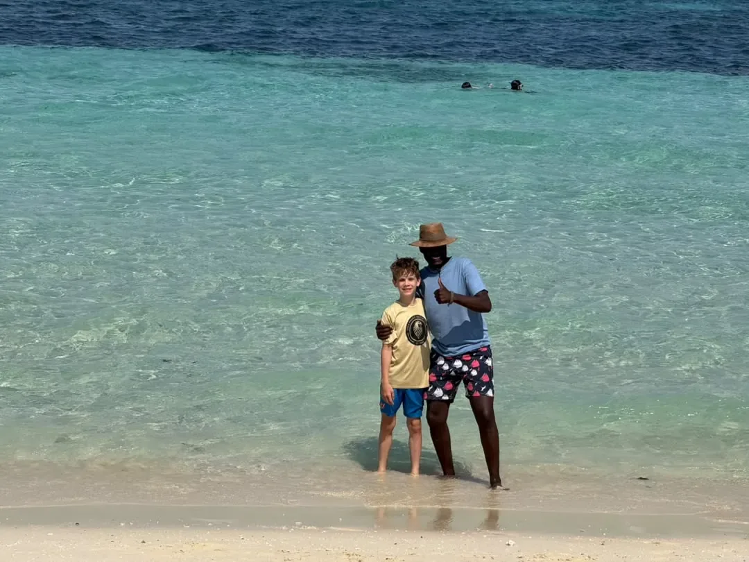 L’archipel de Zanzibar – Our guide and a young guest standing in clear shallow water